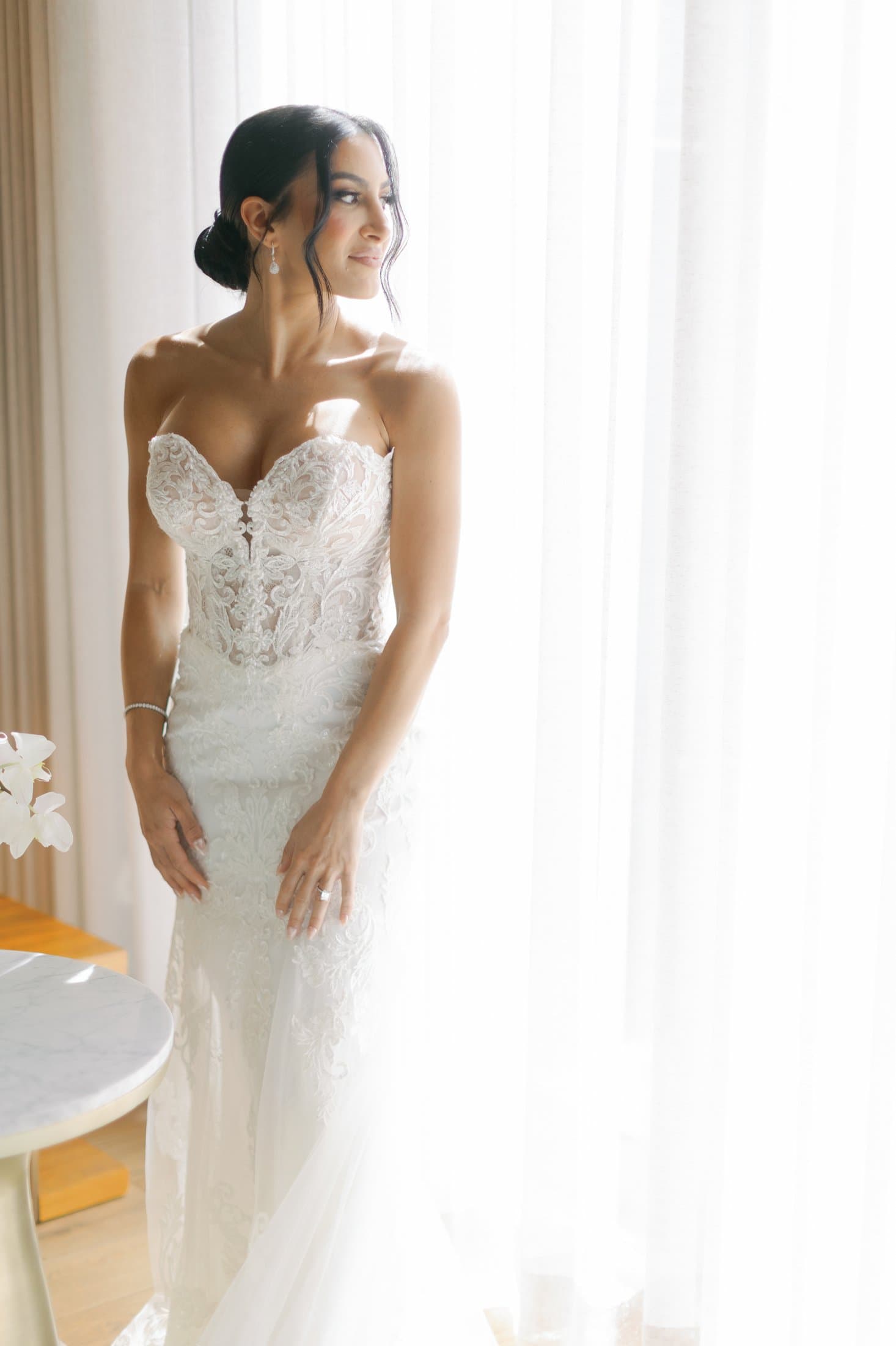 Bride backlit by sheer curtains